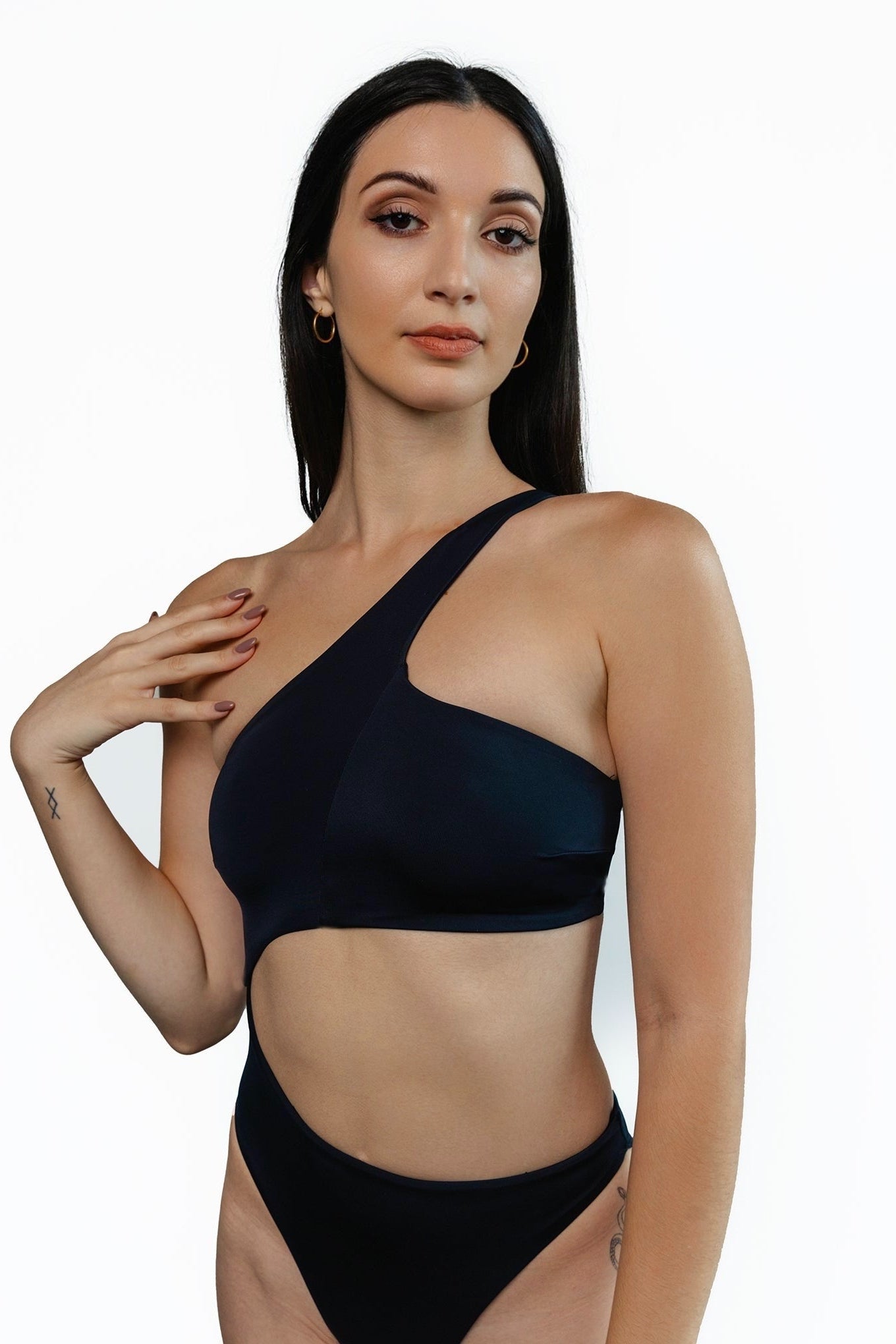 Closeup of the front of Brooklyn swimsuit cutout one-piece in black. Model is standing in front of white background.